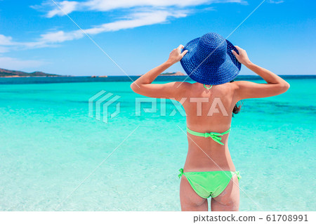 Young woman enjoying the sun sunbathing by perfect turquoise ocean Young woman enjoying the sun sunbathing by perfect turquoise ocean 61708991