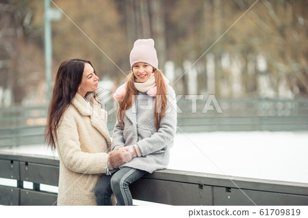 Little adorable girl with her mother skating on ice-rink Little adorable girl with her mother skating on ice-rink 61709819