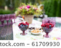 Beautiful glasses of colored purple glass on the table with berries and flowers 61709930