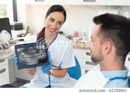 Female dentist showing teeth x-ray on tablet Female dentist showing teeth x-ray on tablet 61709941