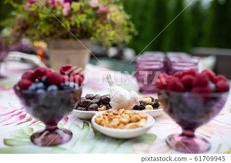 Beautiful glasses of colored purple glass on the table with berries and flowers Beautiful glasses of colored purple glass on the table with berries and flowers 61709945