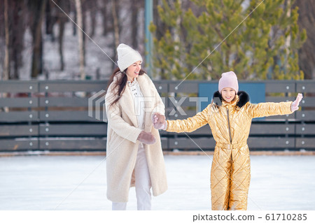 Little adorable girl with her mother skating on ice-rink Little adorable girl with her mother skating on ice-rink 61710285