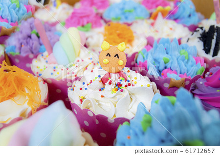 The cup cake bears a beautiful color in the middle of the picture and there are blurry images of the various cup cakes around. The cup cake bears a beautiful color in the middle of the picture and there are blurry images of the various cup cakes around. 61712657