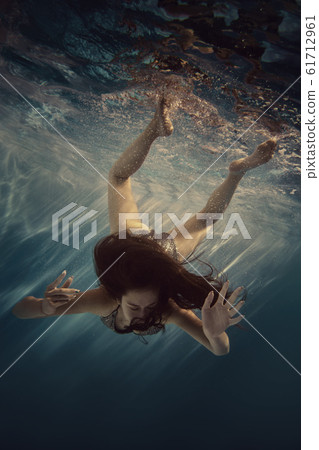 The girl actively swims underwater The girl actively swims underwater 61712961