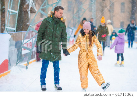 Young dad and adorable little girl have fun on skating rink outdoors Young dad and adorable little girl have fun on skating rink outdoors 61715362