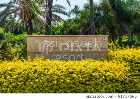 AGIA NAPA, CYPRUS - MAY 26, 2019: the Nissi Beach Resort Hotel signboard, Ayia Napa.This sign is set in the bushes, on the background of palm trees. 61717660
