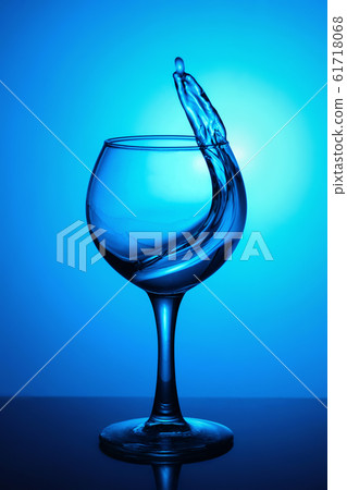 Splash of water in a glass on blue background. Splash of water in a glass on blue background. 61718068