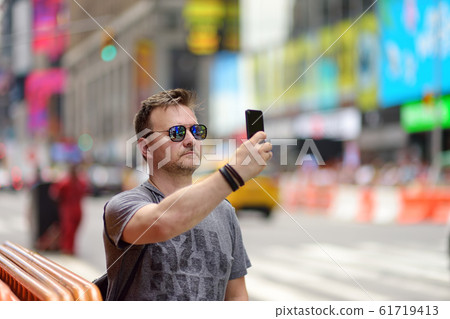 Man tourist shooting or taking selfie on Times Square 61719413