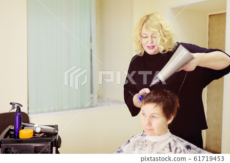 Hairdresser making hairstyle for middle age woman 61719453