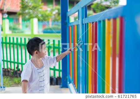 Sad Asian kid behind the grid trying to escape. Sad Asian kid behind the grid trying to escape. 61721765