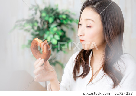 A woman eating a donut 61724258
