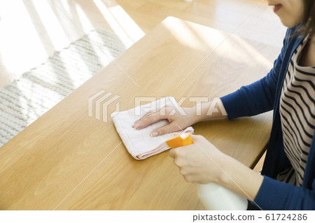Young woman hand wiping center table 61724286