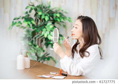 A woman applying lip gloss 61727775