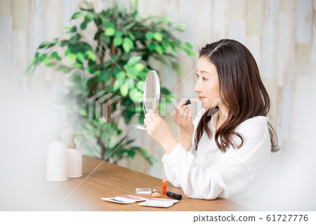 A woman applying lip gloss 61727776