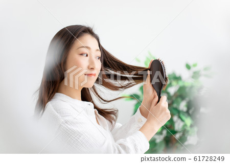 A woman stroking her hair 61728249