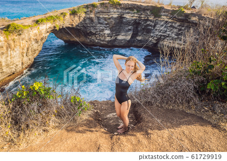 Young woman tourist near Broken Beach in Nusa Penida, Indonesia Angel's BillaBong Beach. Popular Young woman tourist near Broken Beach in Nusa Penida, Indonesia Angel's BillaBong Beach. Popular 61729919