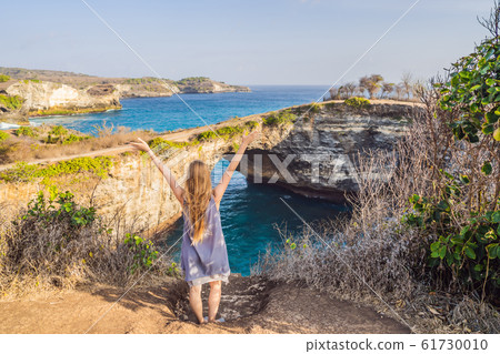 Young woman tourist near Broken Beach in Nusa Penida, Indonesia Angel's BillaBong Beach. Popular 61730010