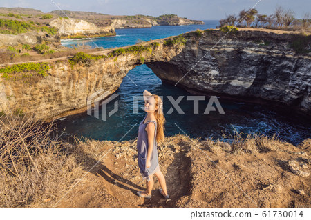Young woman tourist near Broken Beach in Nusa Penida, Indonesia Angel's BillaBong Beach. Popular Young woman tourist near Broken Beach in Nusa Penida, Indonesia Angel's BillaBong Beach. Popular 61730014