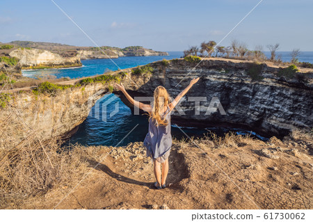 Young woman tourist near Broken Beach in Nusa Penida, Indonesia Angel's BillaBong Beach. Popular Young woman tourist near Broken Beach in Nusa Penida, Indonesia Angel's BillaBong Beach. Popular 61730062