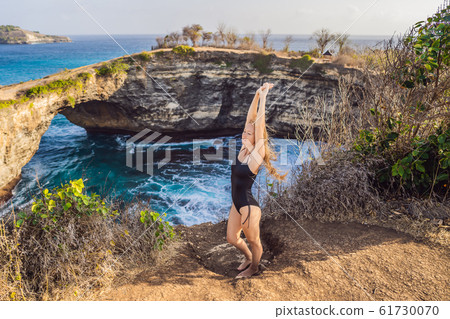 Young woman tourist near Broken Beach in Nusa Penida, Indonesia Angel's BillaBong Beach. Popular Young woman tourist near Broken Beach in Nusa Penida, Indonesia Angel's BillaBong Beach. Popular 61730070