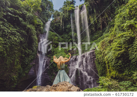 Woman in turquoise dress at the Sekumpul waterfalls in jungles on Bali island, Indonesia. Bali 61730172