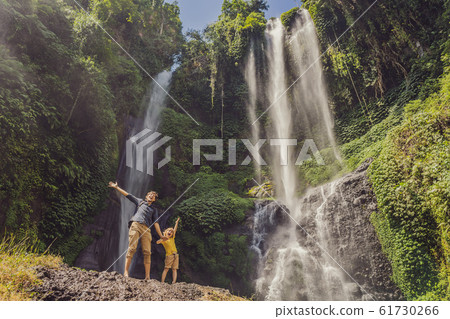 Dad and son at the Sekumpul waterfalls in jungles on Bali island, Indonesia. Bali Travel Concept 61730266