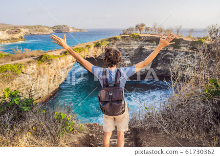 Young man tourist near Broken Beach in Nusa Penida, Indonesia Angel's BillaBong Beach. Popular Young man tourist near Broken Beach in Nusa Penida, Indonesia Angel's BillaBong Beach. Popular 61730362