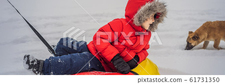 Child having fun on snow tube. Boy is riding a tubing. Winter fun for children BANNER, LONG FORMAT 61731350