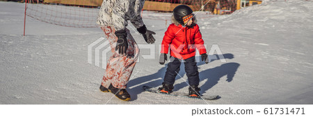 Dad teaches son snowboarding. Activities for children in winter. Children's winter sport. Lifestyle Dad teaches son snowboarding. Activities for children in winter. Children's winter sport. Lifestyle 61731471