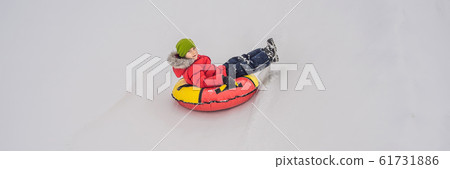 Child having fun on snow tube. Boy is riding a tubing. Winter fun for children BANNER, LONG FORMAT 61731886