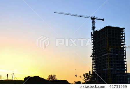 Tower crane constructing a new residential building at a construction site at sunset background. 61731969