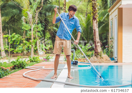 Cleaner of the swimming pool . Man in a blue shirt with cleaning equipment for swimming pools, sunny Cleaner of the swimming pool . Man in a blue shirt with cleaning equipment for swimming pools, sunny 61734637