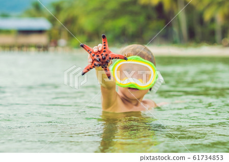 A boy and a red starfish against the backdrop of the sea 61734853
