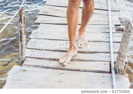 Legs on the old pier on the background of the sea 61735005