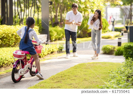 a girl try to ride a bicycle by traing from her a girl try to ride a bicycle by traing from her 61735041