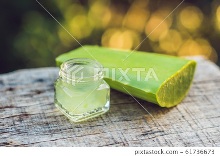Slices of a aloe vera leaf and a bottle with transparent gel for medicinal purposes, skin treatment and cosmetics, close up 61736673