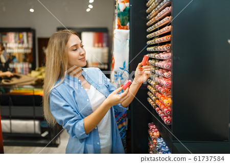 Seamstress buying threads in textile workshop 61737584