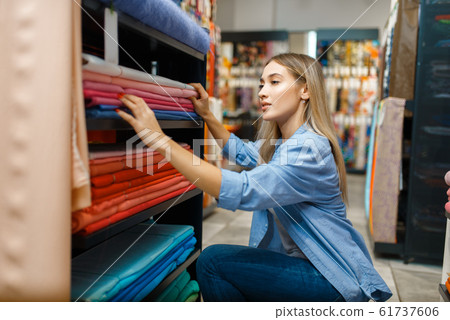 Saleswoman measures fabric in textile store Saleswoman measures fabric in textile store 61737606