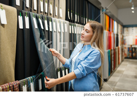 Saleswoman measures fabric in textile store 61737607