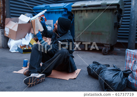 Dirty drunk beggar lies in garbage at the trashcan Dirty drunk beggar lies in garbage at the trashcan 61737719