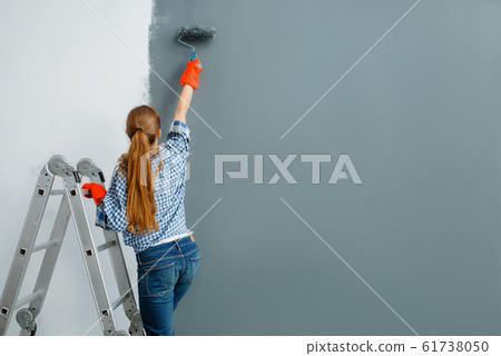 Female house painter paints walls indoor Female house painter paints walls indoor 61738050