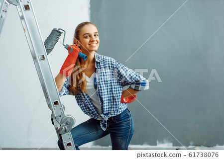 Female house painter paints wall in grey color Female house painter paints wall in grey color 61738076