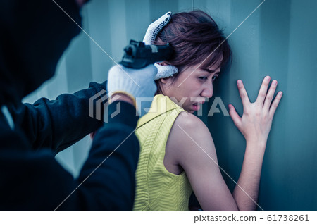 Bandit wear black mask and black clothes using gun point to head of woman for rob money and hurting her. 61738261