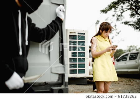 woman walk and chat with friend on smartphone while villains wear black mask and black clothes holding knife are dodging the corner of the building. 61738262