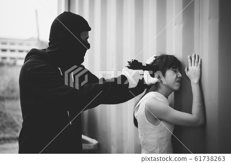 Bandit wear black mask and black clothes using gun point to head of woman for rob money and hurting her. black and white picture 61738263