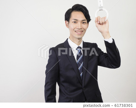 Businessman holding on a strap and smiling 61738301