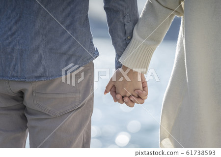 Hands of a young couple holding hands 61738593