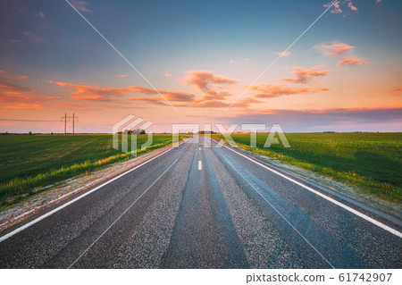 Asphalt Country Open Road Through Spring Fields And Meadows In Sunny Evening. Landscape In Early Summer Season At Sunny Sunset Asphalt Country Open Road Through Spring Fields And Meadows In Sunny Evening. Landscape In Early Summer Season At Sunny Sunset 61742907