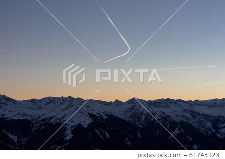 Panoramic sunset view chemtrails Saalbach snowy mountains chemtrail sunset sky from plane Panoramic sunset view chemtrails Saalbach snowy mountains chemtrail sunset sky from plane 61743123