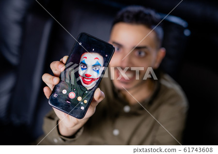 Hand of young smiling man holding smartphone while using multimedia application 61743608